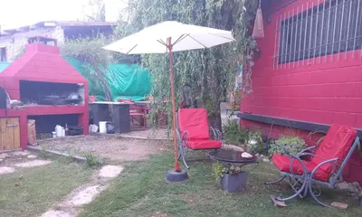 a patio with two red chairs and an umbrella at La Bicicleta solar casa abierta in Villa Independencia