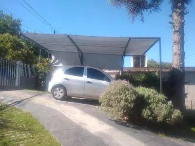 a car parked under a covering in a driveway at La Bicicleta solar casa abierta in Villa Independencia