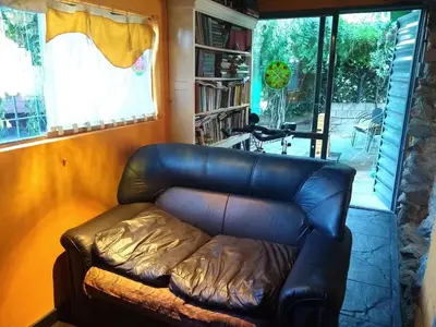 a leather couch in a living room with a window at La Bicicleta solar casa abierta in Villa Independencia