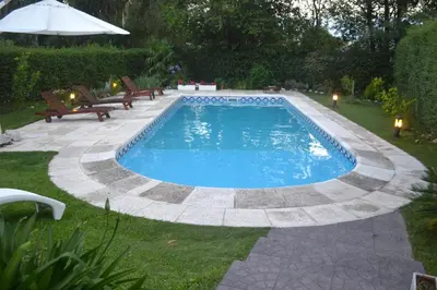 a swimming pool in a yard with benches and an umbrella at Casa Simona Villa General Belgrano in Villa General Belgrano