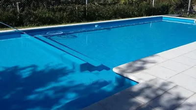 a swimming pool with blue water in a yard at Cabañas Alma Comechingon in Villa Cura Brochero