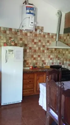 a kitchen with a white refrigerator and a sink at Cabañas Alma Comechingon in Villa Cura Brochero
