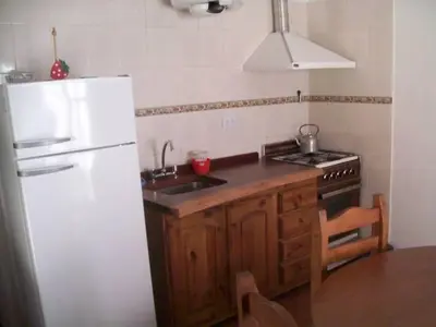 a kitchen with a white refrigerator and a sink at Cabañas Alma Comechingon in Villa Cura Brochero