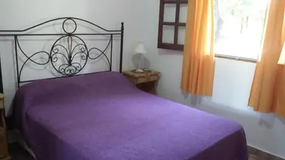 a purple bed in a bedroom with a window at Cabañas Alma Comechingon in Villa Cura Brochero