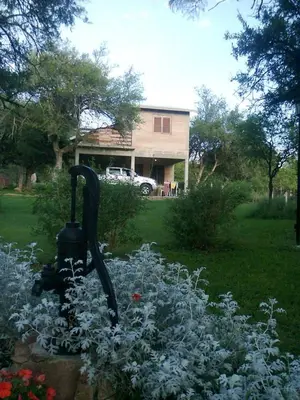 a garden with a statue in front of a house at Cabañas Alma Comechingon in Villa Cura Brochero