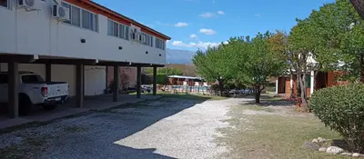 a dirt road next to a building with a truck at Apart hotel Residencial El Puma in Mina Clavero