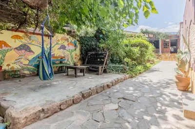 a patio with a bench and a wall with a mural at Andamundos Hostel in Mina Clavero