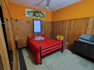 a bedroom with a red bed and wooden walls at Andamundos Hostel in Mina Clavero