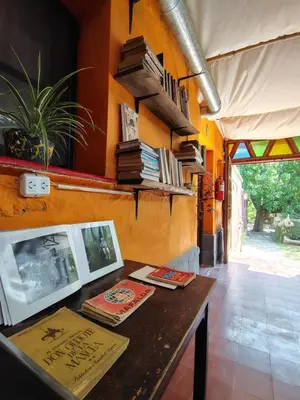 a room with a table with books on a wall at Andamundos Hostel in Mina Clavero