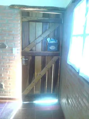 a wooden shelf in a room with a brick wall at Cálidas Cabañas Las Piedras 2 , Villa Cura Brochero con wi fi in Villa Cura Brochero