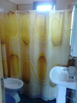 a bathroom with a yellow shower curtain and a sink at Cálidas Cabañas Las Piedras 2 , Villa Cura Brochero con wi fi in Villa Cura Brochero