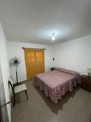a bedroom with a bed and a lamp and a chair at La Elvira in Alta Gracia