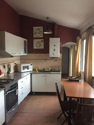 a kitchen with white cabinets and a wooden table with a tableablish at Gimenoz Apart in Nono