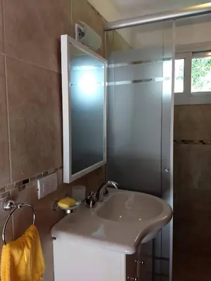 a bathroom with a sink and a mirror and a shower at Mirador Suites & Aptos in Villa General Belgrano