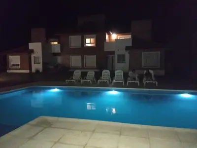 a swimming pool at night with chairs and a building at Mirador Suites & Aptos in Villa General Belgrano