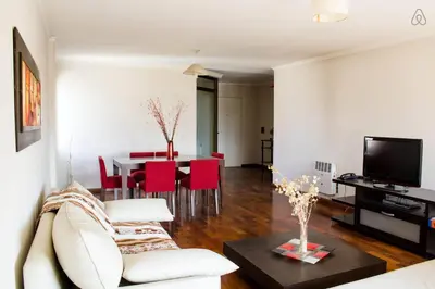 a living room with a couch and a table with red chairs at Departamento enorme sobre Cañada Patio Olmos in Cordoba