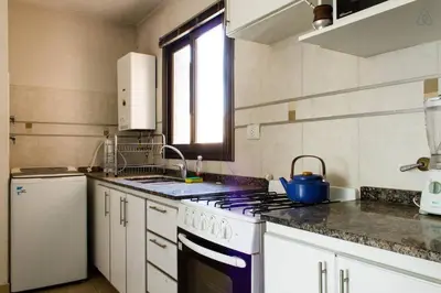 a kitchen with white cabinets and a stove top oven at Departamento enorme sobre Cañada Patio Olmos in Cordoba
