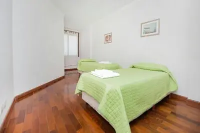 a bedroom with two green beds and a wooden floor at Departamento enorme sobre Cañada Patio Olmos in Cordoba