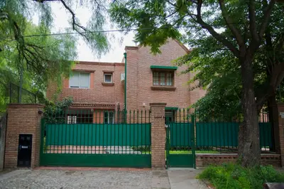 a brick house with a green fence and a tree at Casa en Córdoba in Cordoba