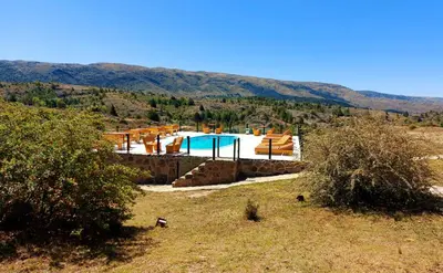 a swimming pool in a field with mountains in the background at Complejo Apus in La Cumbrecita