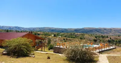 a house with a pool and mountains in the background at Complejo Apus in La Cumbrecita