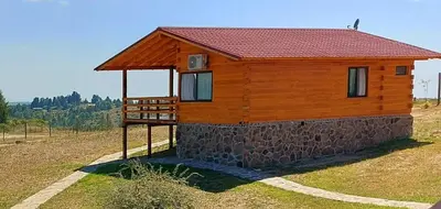 a wooden cabin with a red roof on a field at Complejo Apus in La Cumbrecita