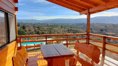 a wooden table and chairs on the balcony of a cabin at Complejo Apus in La Cumbrecita