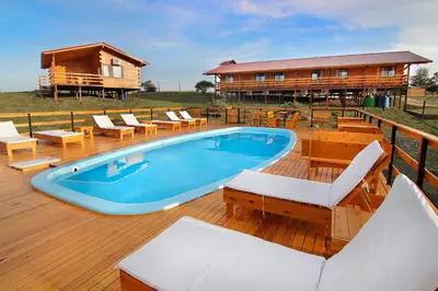 a pool on a deck with chairs and a house at Complejo Apus in La Cumbrecita