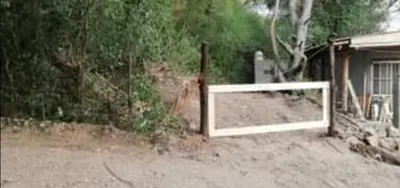 a white gate in the dirt next to a house at Las zarinas 2 in Trapiche