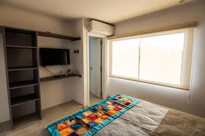 a room with a bed with a window and a television at Hotel Las Piedras in Villa Cura Brochero