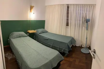 two beds in a room with green walls and a window at Departamento en Nueva Cordoba, 2 dormitorios in Cordoba
