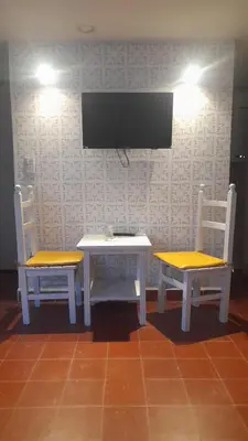 a table and two chairs with a tv on a wall at El mirador de estrellas in Santa Rosa de Calamuchita