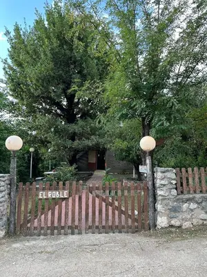a wooden fence in front of a house with a tree at El Roble in Merlo