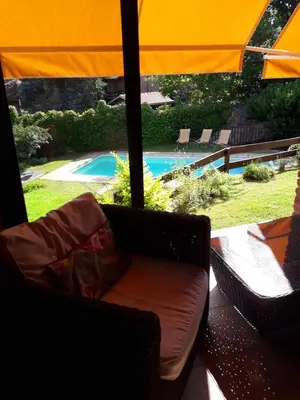a porch with a couch and an umbrella and a pool at Casa frente al rio icho cruz 10 personas ideal varias parejas o familias in Villa Icho Cruz