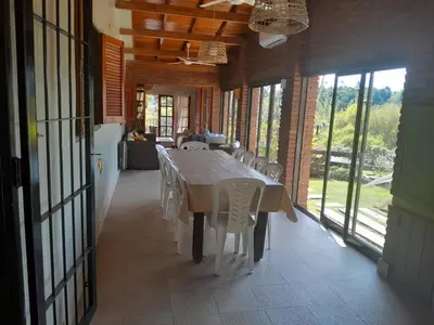 a dining room with a table and chairs and windows at Casa frente al rio icho cruz 10 personas ideal varias parejas o familias in Villa Icho Cruz