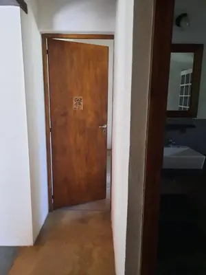 a wooden door in a bathroom with a sink at La Roja y Barro tal vez in Los Molles