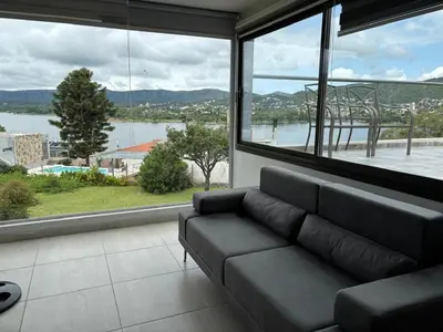 a living room with a couch and a large window at casa del alto categoria vista plena lago pileta in Villa Carlos Paz