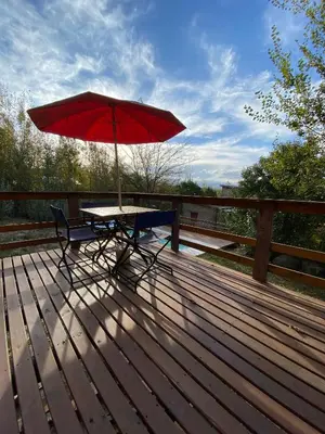a picnic table with a red umbrella on a wooden deck at Cabañas San Urbano 1 in Villa Yacanto