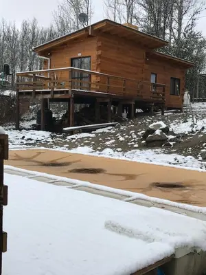 a log cabin with a deck in the snow at Cabañas San Urbano 1 in Villa Yacanto