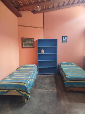 two beds in a room with orange walls and blue cabinets at Cabañas Entrelomas in Nono