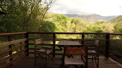 a table and chairs on a deck with a view at Cabañas Entrelomas in Nono