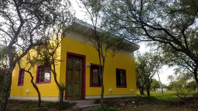 a yellow house with a red door and some trees at apartamento VINTAGE LU in Merlo