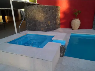 a swimming pool with a blue tub next to a building at Hotel Edelweiss in Villa General Belgrano
