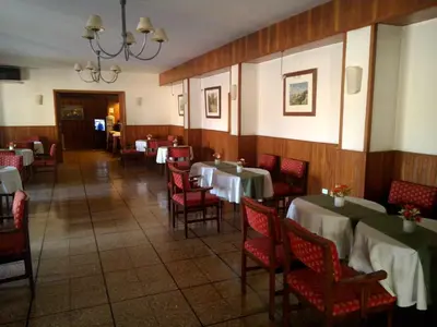 a dining room with tables and red chairs at Hotel Edelweiss in Villa General Belgrano