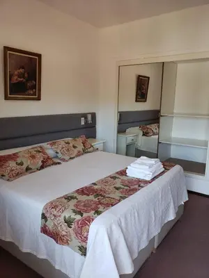 a bedroom with a large bed with white sheets and flowers at Hotel Edelweiss in Villa General Belgrano