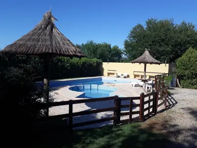 a swimming pool with a fence and an umbrella at Cabañas El Vallecito in Villa del Dique
