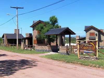 a building with a sign next to a dirt road at Cabañas El Vallecito in Villa del Dique