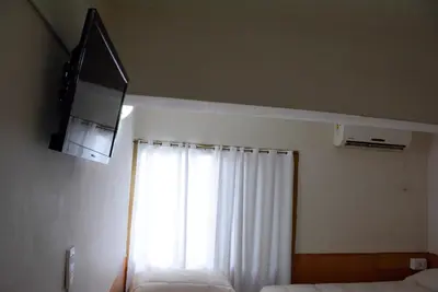 a bedroom with two beds and a window with a television at Hotel Menossi in Río Cuarto