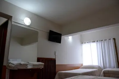 a room with two beds and a television on the wall at Hotel Menossi in Río Cuarto