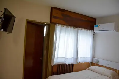 a bedroom with a bed and a window and a television at Hotel Menossi in Río Cuarto